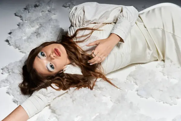 Dressed in an elegant outfit, a young woman exudes confidence while lying on a white surface. — Stock Photo