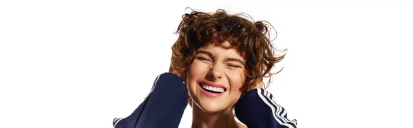 A young woman with curly hair shows a joyful expression while playfully covering her ears. — Stock Photo
