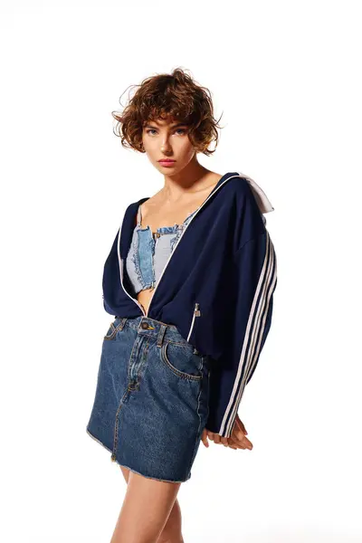 A young woman showcases unique denim styles with an emotional expression in a bright studio. — Stock Photo