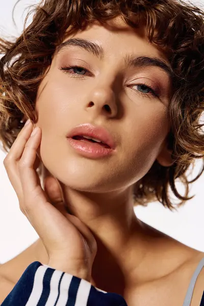 A young woman with beautiful curls gently touches her face, showcasing strong emotions. — Stock Photo