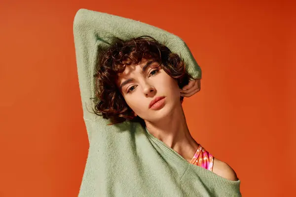 Une jeune femme aux cheveux bouclés met en valeur ses émotions sur un fond orange vif. — Photo de stock