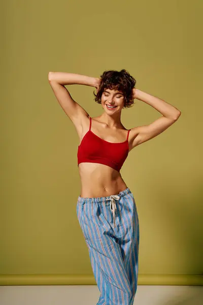 A cheerful young woman poses in stylish loungewear against a vibrant backdrop. — Stock Photo