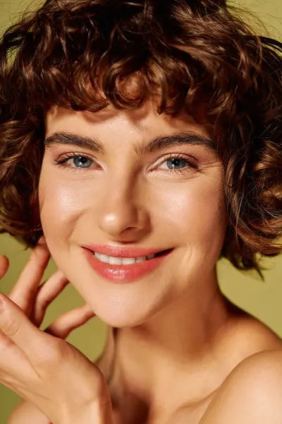 A young woman shares her infectious smile while lightly touching her face, radiating joy. — Stock Photo