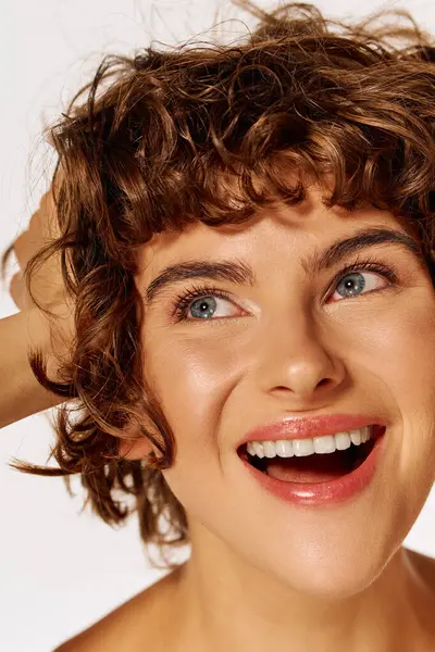 A young woman with curly hair beams with joy in a lively atmosphere. — Stock Photo
