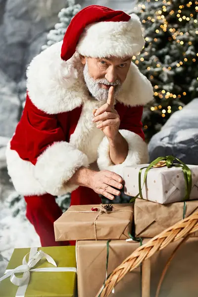 A jolly figure dressed as Santa carefully arranges beautifully wrapped gifts in a snowy landscape. — Stock Photo