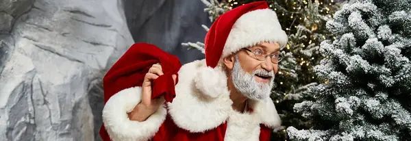 Santa Claus smiles brightly while holding a red sack, surrounded by festive decorations. — Stock Photo