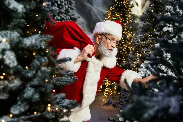 Amidst beautifully decorated trees, Santa Claus quietly arranges holiday gifts for children. — Stock Photo