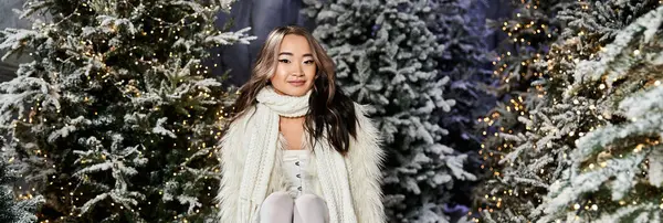 Une jeune femme jouit d'une atmosphère festive parmi les arbres de Noël magnifiquement éclairés. — Photo de stock