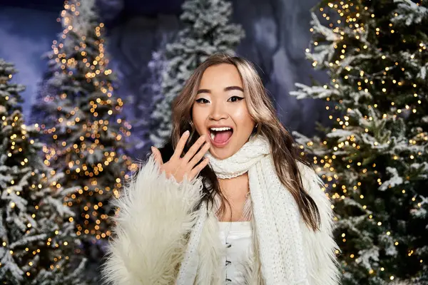 A young woman enjoys the merry atmosphere amid sparkling trees decorated for the holiday season. — Stock Photo