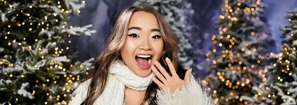 A cheerful individual expresses excitement amid snowy trees adorned with twinkling lights. — Stock Photo