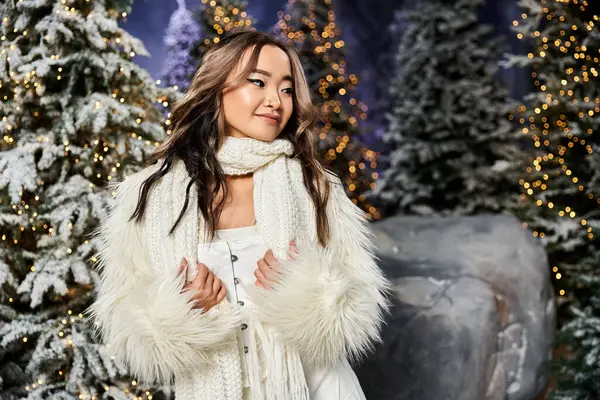 A young person in a cozy outfit embraces the holiday joy surrounded by snowy trees and lights. — Stock Photo