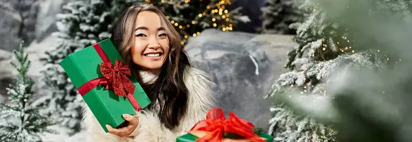A delighted person poses with a beautifully wrapped gift surrounded by Christmas decorations. — Stock Photo