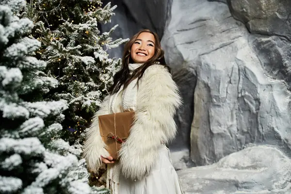 A joyful woman holds a wrapped gift in a snowy winter wonderland. — Stock Photo