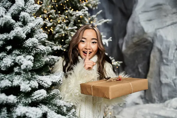 A person playfully holds a gift while sharing a secret in a winter wonderland filled with joy. — Stock Photo