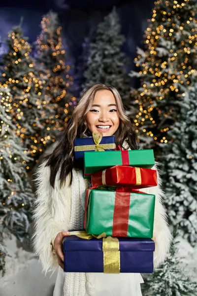 A smiling individual holds vibrant presents amidst a festive winter wonderland. — Stock Photo