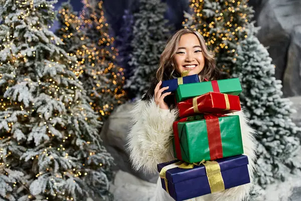 A cheerful individual holds vibrant presents while surrounded by a winter wonderland. — Stock Photo