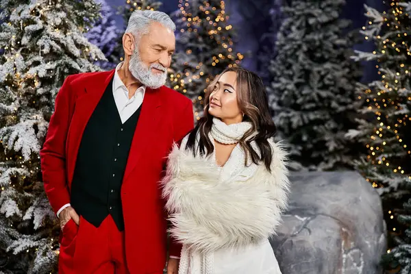 A man and woman enjoy a festive moment by lovely, lit Christmas trees. — Stock Photo