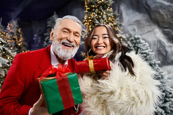 A cheerful man and woman share holiday gifts while surrounded by a magical Christmas setting. — Stock Photo