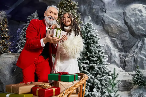 A joyful couple beams with excitement, holding a wrapped gift amid festive decor. — Stock Photo