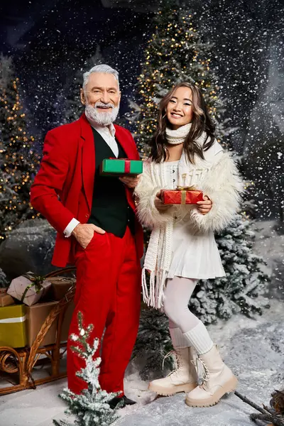 Un Babbo Natale gioioso e una donna con regali colorati celebrano in una scena nevosa e festosa. — Foto stock