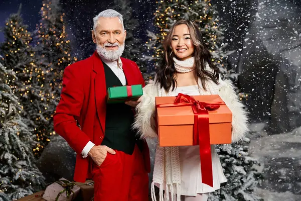 A man and woman happily share wrapped gifts in a festive winter wonderland. — Stock Photo