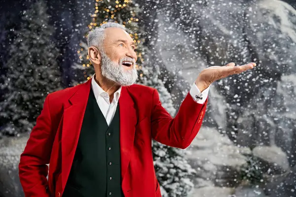 A cheerful gentleman dressed in red spreads holiday cheer amidst a snowy winter wonderland — Stock Photo
