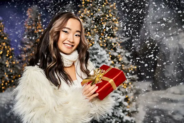 A cheerful woman with long hair embraces the holiday spirit while holding a red gift. — Stock Photo