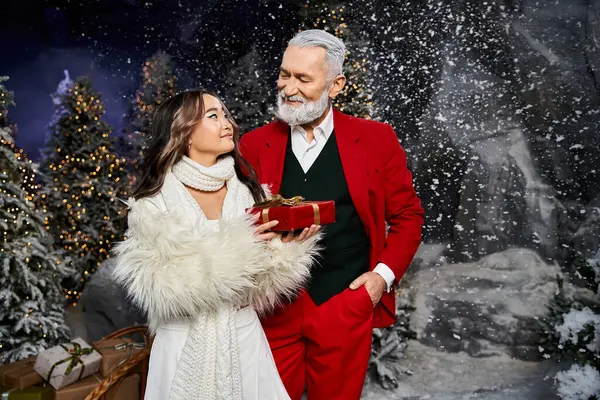 Two people celebrate the festive season surrounded by snow covered trees and sparkling lights. — Stock Photo