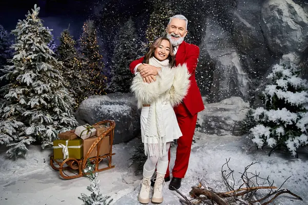 A man and woman embrace warmly in a festive snowy landscape, surrounded by holiday decorations. — Stock Photo