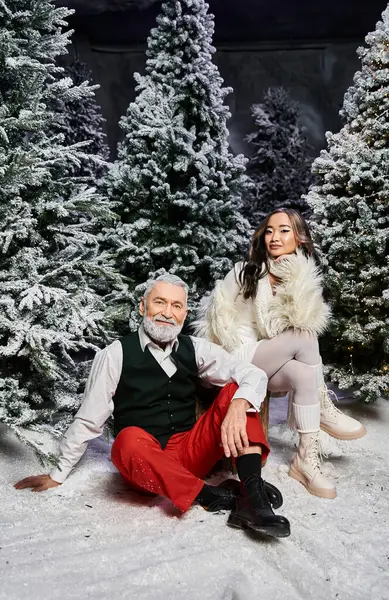 A stylish couple enjoys a festive moment together, surrounded by snowy Christmas trees. — Stock Photo
