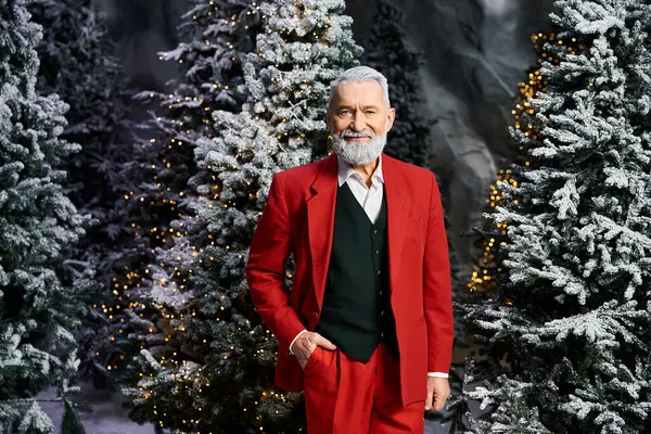 A man in a vibrant red suit stands confidently among beautifully adorned snowy trees. — Stock Photo