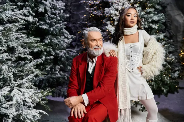 A charming duo poses in winter attire amid frosted Christmas trees, capturing holiday spirit. — Stock Photo