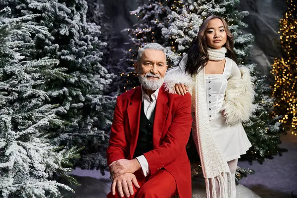 A cheerful celebration features a man in red and a woman in white amidst snowy pine trees. — Stock Photo