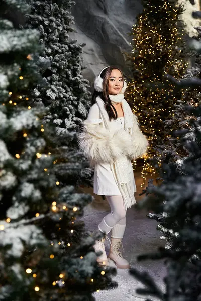 In einer zauberhaften Winterlandschaft bewundert eine junge Frau wunderschön beleuchtete Weihnachtsbäume im Schnee. — Stockfoto