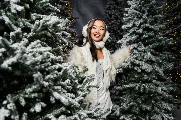 A cheerful woman wanders through a winter wonderland filled with snowy Christmas trees. — Stock Photo