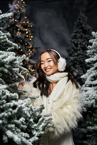 A cheerful individual enjoys a festive atmosphere, surrounded by frosted trees and lights. — Stock Photo