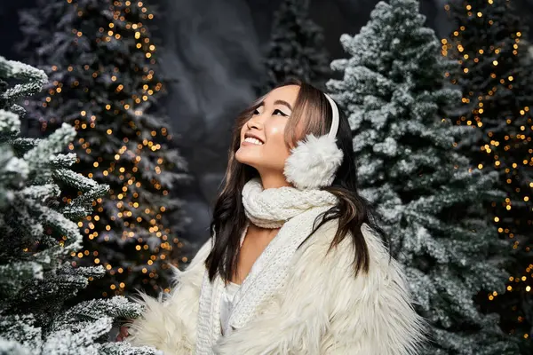 A happy woman in warm clothes admires beautifully lit Christmas trees. — Stock Photo