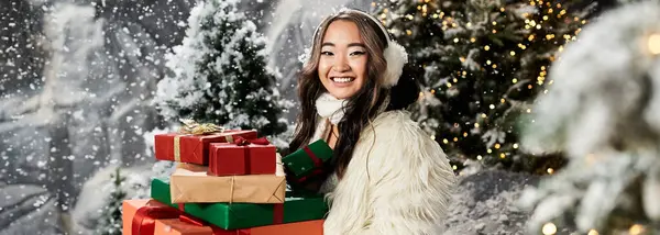 A cheerful woman holds vibrant gifts while enjoying the festive winter atmosphere. — Stock Photo