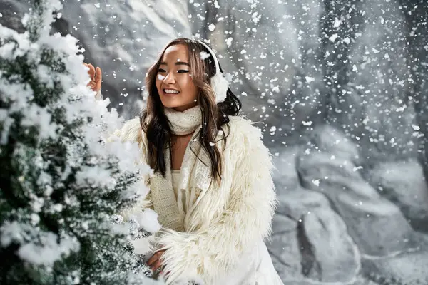 Une femme joyeuse interagit avec les arbres enneigés pendant la période des fêtes de Noël. — Photo de stock