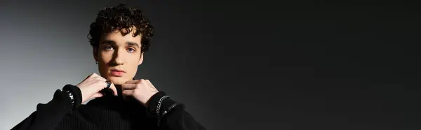 A fashionable young man stands elegantly in a black turtleneck, exuding charm against a muted background. — Stock Photo