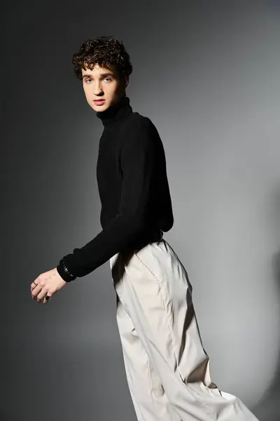 A stylish young man poses confidently on a dark grey background, showcasing elegance and fashion. — Stock Photo