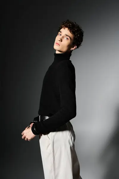 A handsome young man strikes a confident pose, showcasing his fashion-forward look in a sleek black turtleneck. — Stock Photo