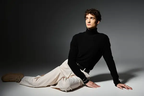 Un joven con estilo se relaja con gracia en un cuello alto negro con clase, mostrando su sentido de la moda. - foto de stock