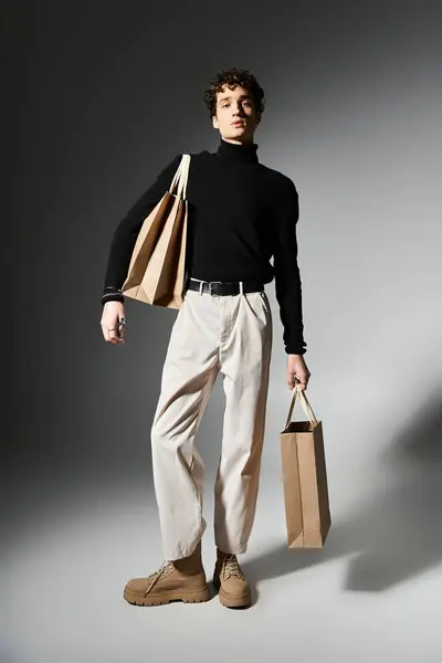 Ein modischer junger Mann hält Einkaufstüten in der Hand und präsentiert seine lockigen Haare und sein trendiges Outfit bei Veranstaltungen am Black Friday. — Stockfoto