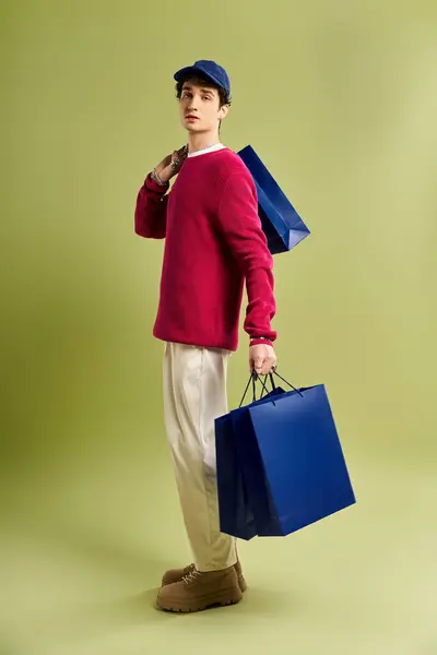 Um jovem elegante com cabelo encaracolado alegremente mantém sacos de compras, celebrando o espírito Black Friday. — Fotografia de Stock