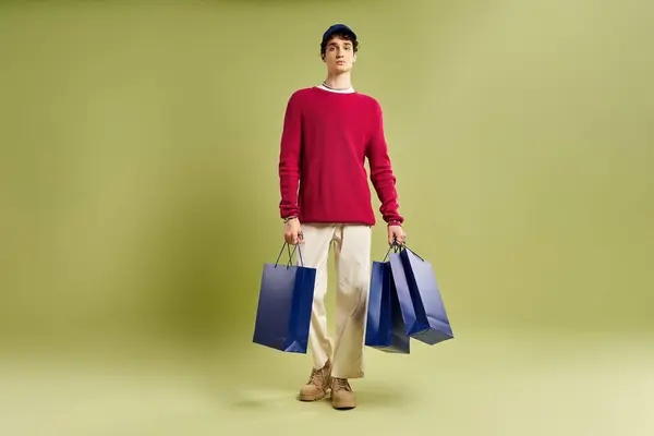 Um jovem elegante com cabelo encaracolado mantém sacos de compras excitados, comemorando Black Friday em um estúdio. — Fotografia de Stock