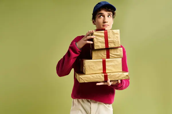 A young man with curly hair clutches beautifully wrapped Christmas gifts in a bright studio. — Stock Photo