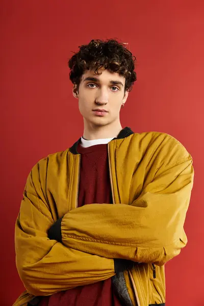 A stylish young man in a yellow jacket stands confidently with his arms crossed, exuding charisma. — Stock Photo