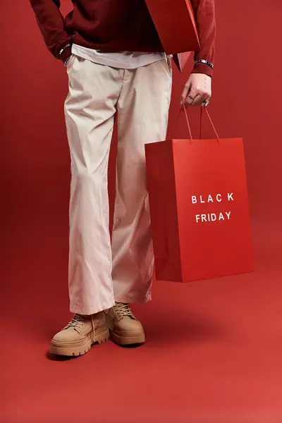 A stylish young man with curly hair joyfully holds shopping bags in a bright studio environment. — Stock Photo