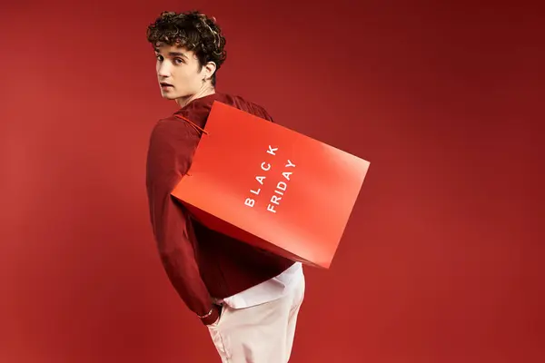 A handsome man with curly hair showcases his shopping bags, embodying the excitement of Black Friday. — Stock Photo